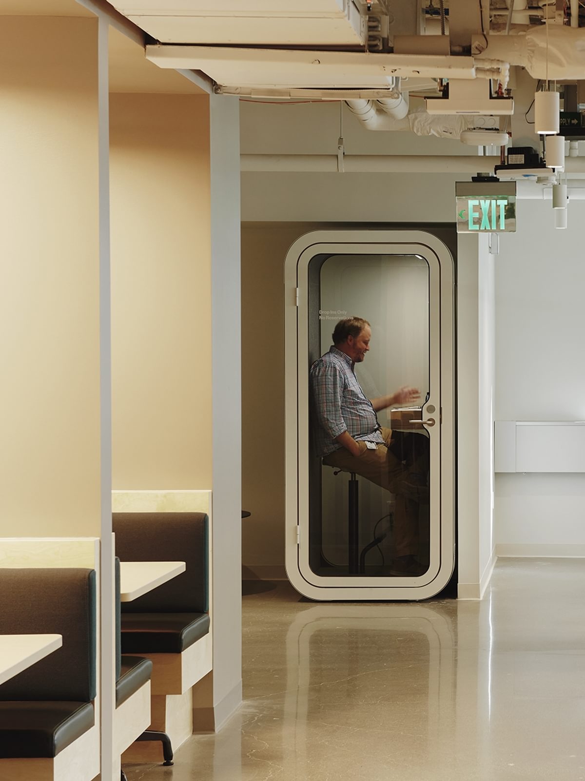 A man takes a meeting in the quiet solitude of a phone booth at The Engine.