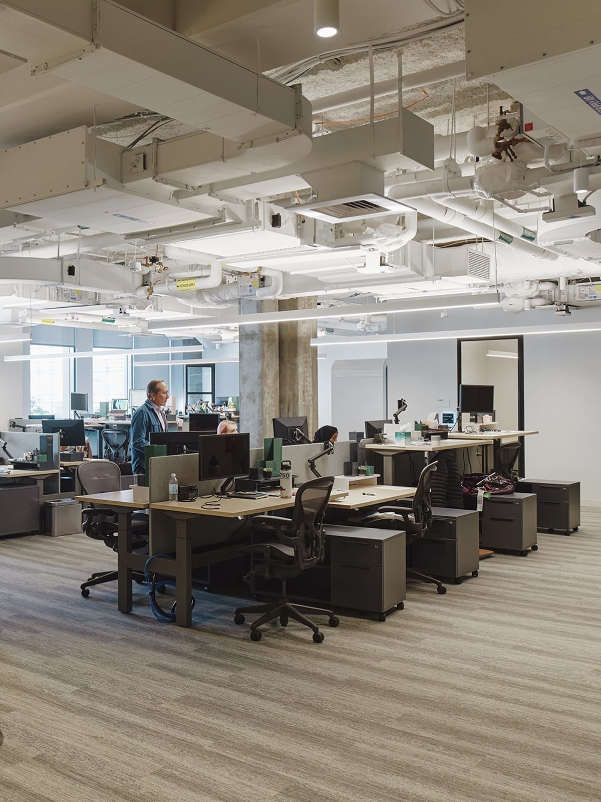 A view of a private office space at The Engine, featuring rows of desks in an open floor plan.