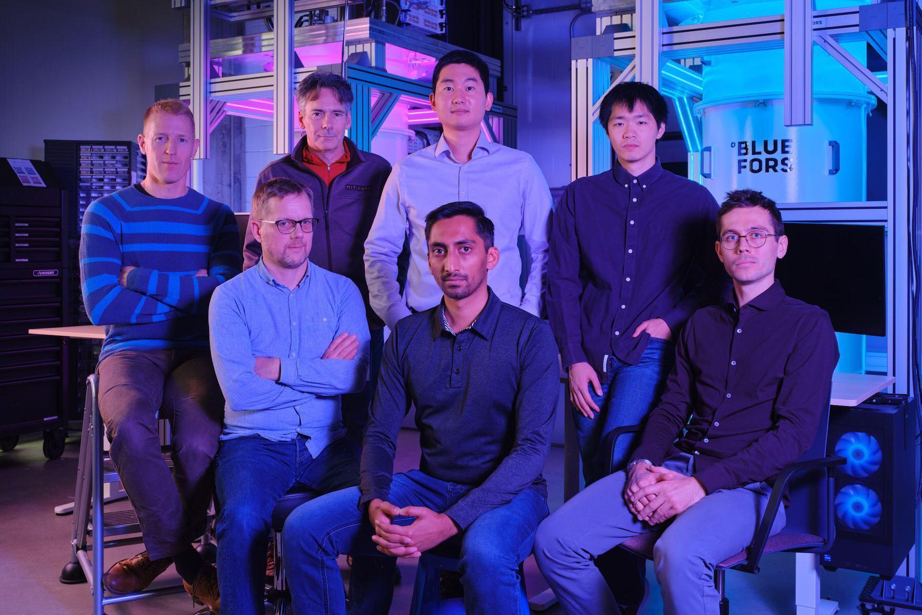 The Atlantic Quantum team pose for a photo in a darkly lit room.