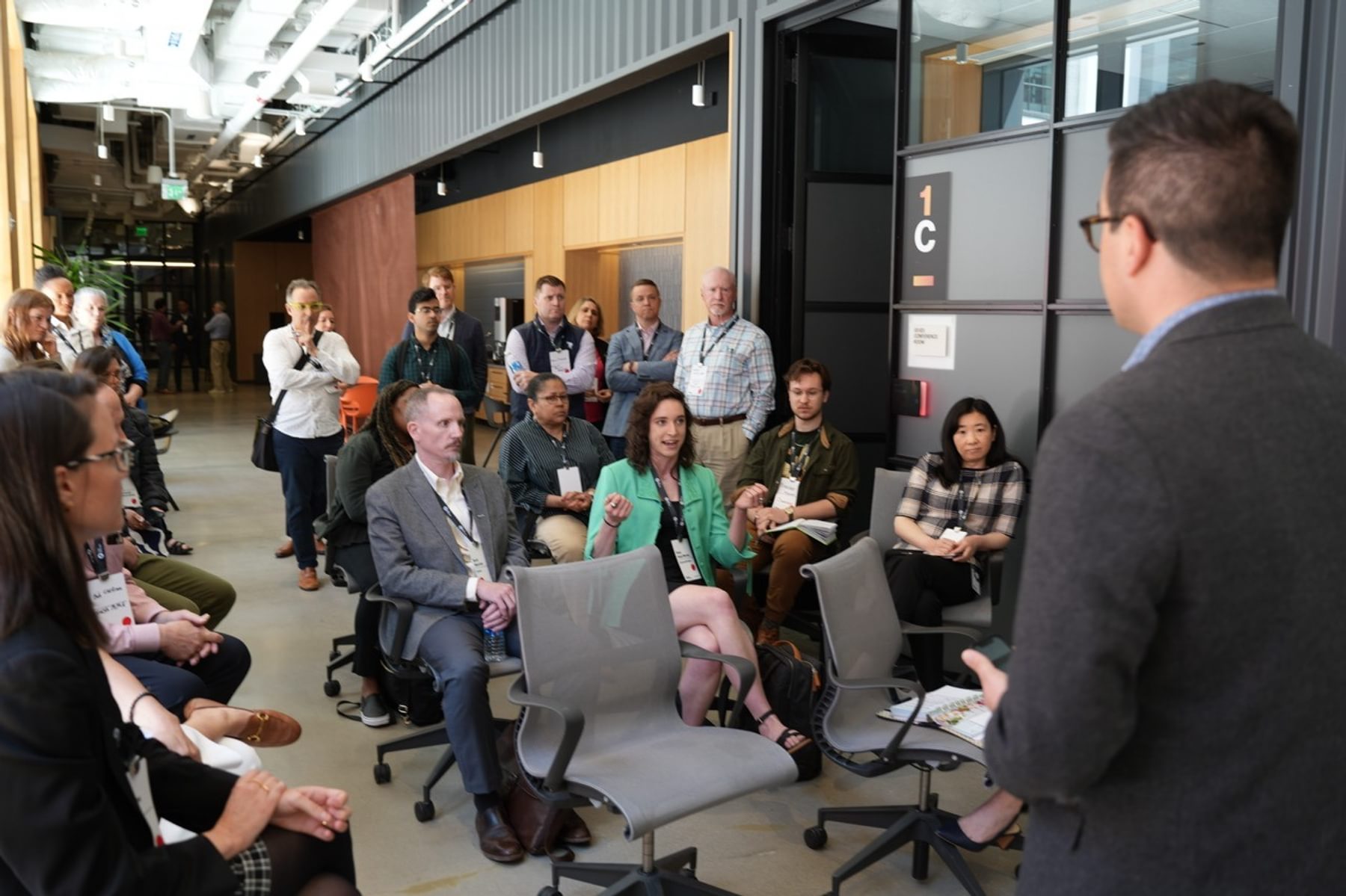 A group of people, some sitting and some standing, talk during a session in The Engine's event space.
