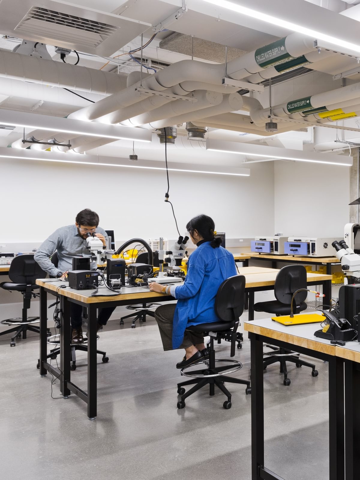 Electrical engineers peer through microscopes in The Engine's electronics shop.