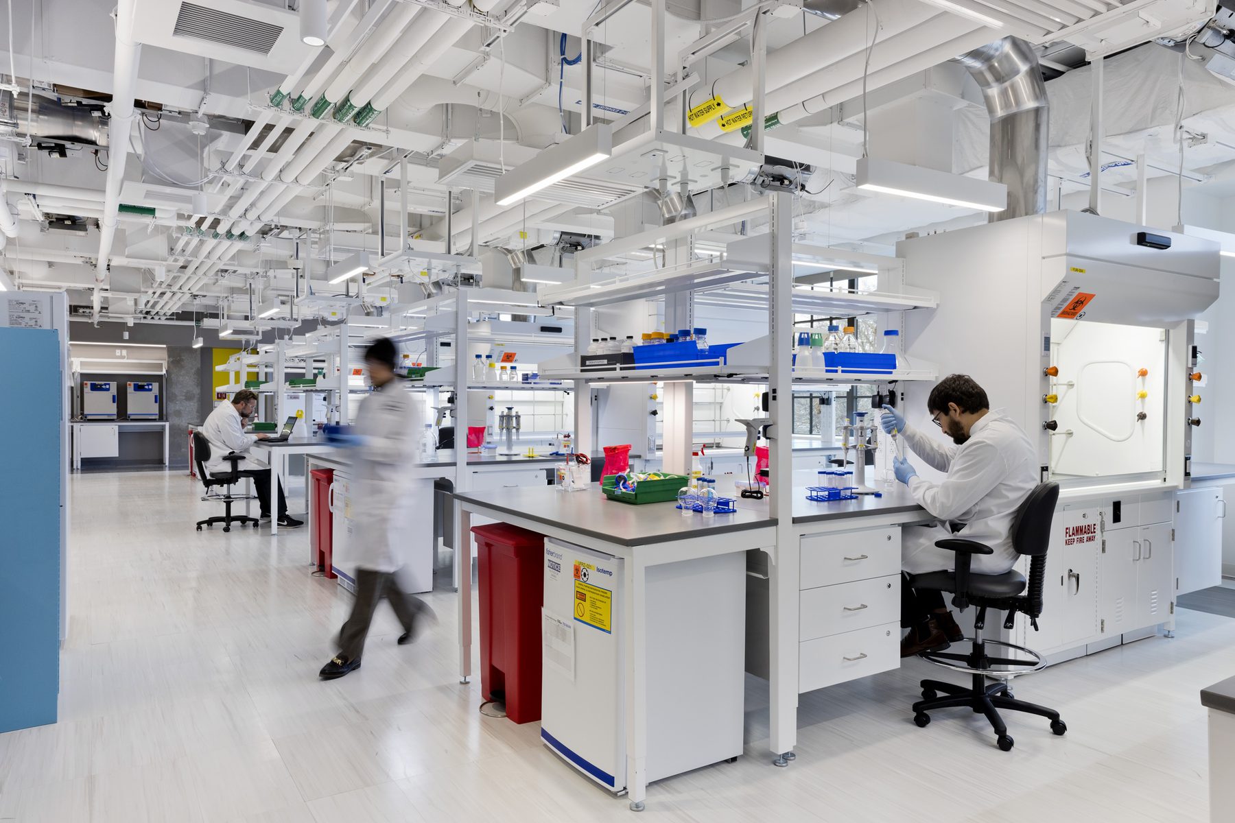 Scientists work in The Engine's BSL-2 wet lab space, with rows of lab benches visible.