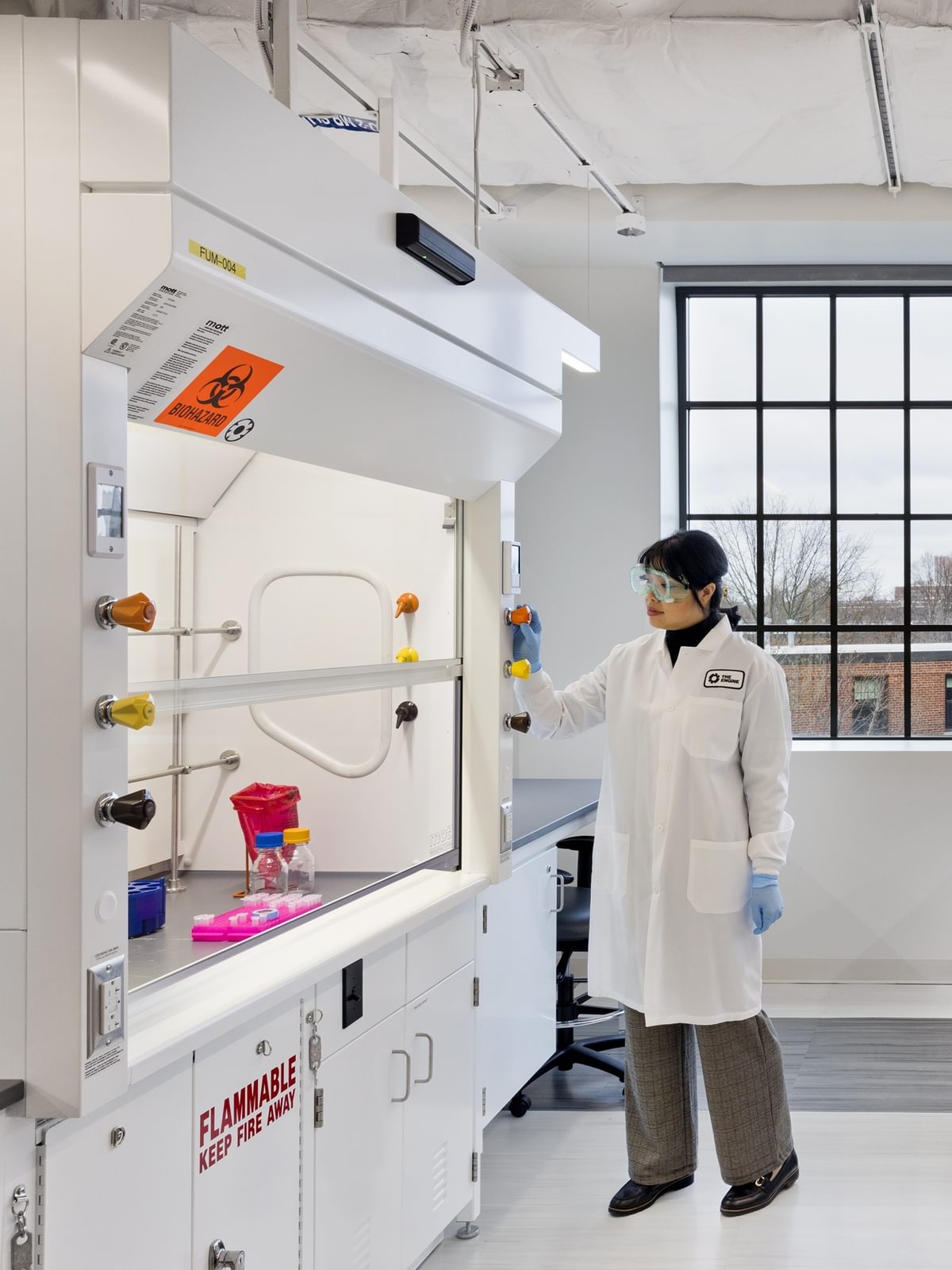 A scientist works under a fume hood in The Engine's BSL-2 wet lab space.