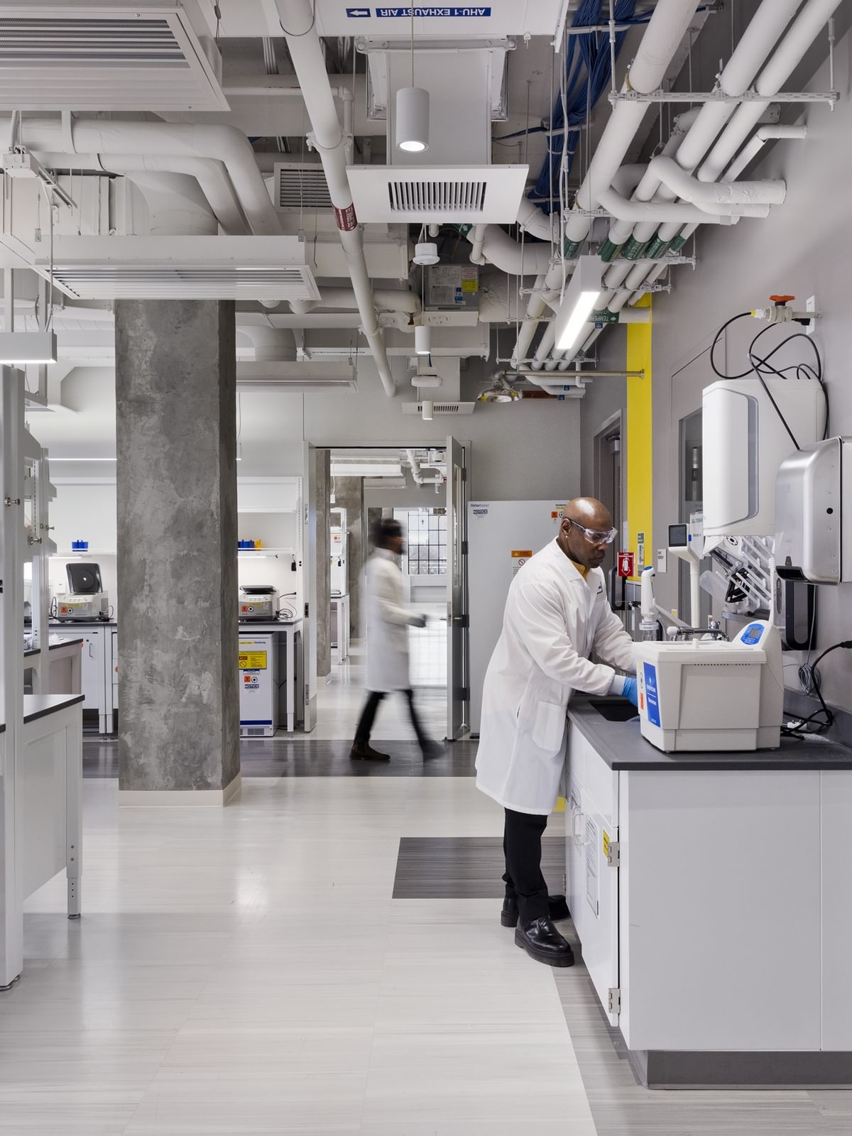 Scientists wearing lab coats and safety goggles work in The Engine's BSL-2 wet lab space.