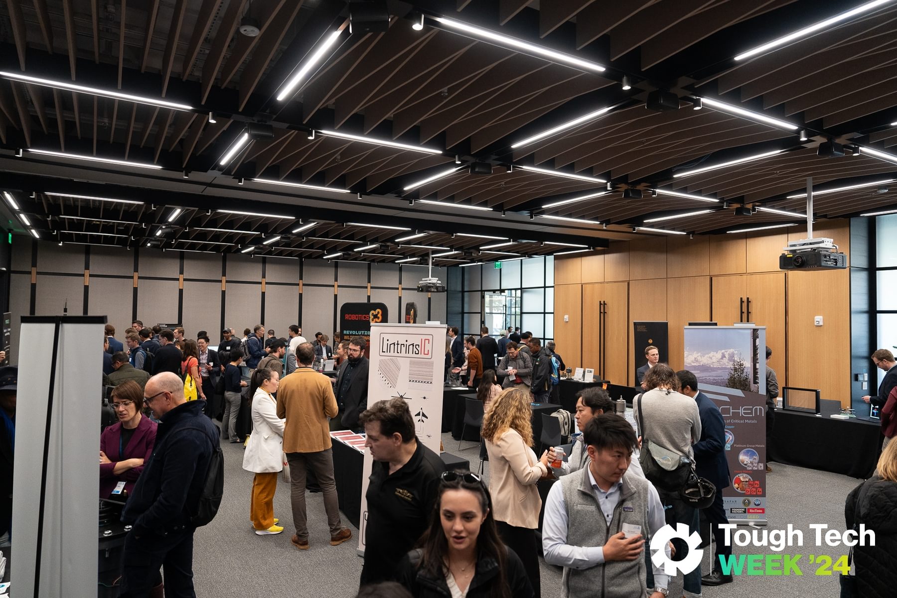 Attendees congregate at vendor booths in The Engine's event space during Tough Tech Week 2024.