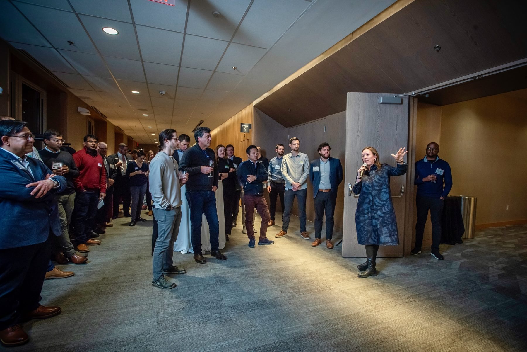 The Engine's President and CEO Emily Knight speaks to a crowd of people gathered in a hallway.